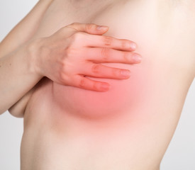 Breast cancer self check. Young woman examining her breast for lumps or signs of breast cancer....