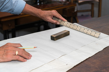 Fototapeta na wymiar dressmaker drawing tailor pattern with pencil for a suit on the table 