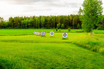 Outdoor archery targets on grass field surrounded by forest in the summer evening. - 114288877