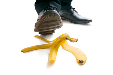 Walking businessman is going to slip on banana peel.
