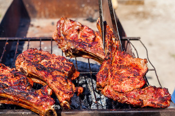 Roasted meat on the grill with male hand.