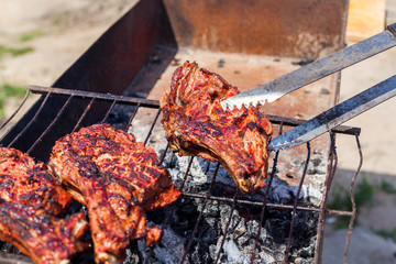 Roasted meat on the grill with male hand.