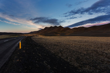 Fototapeta na wymiar Dark road in north Iceland at sunset. Mountains on the horizon,