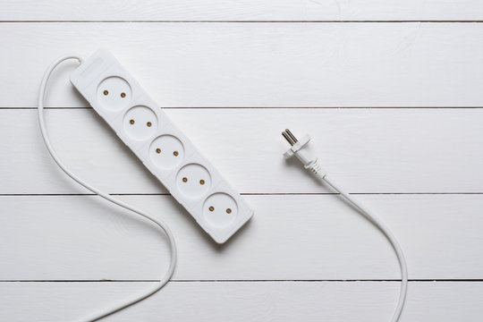 Flat lay - white extension cord on wooden floor