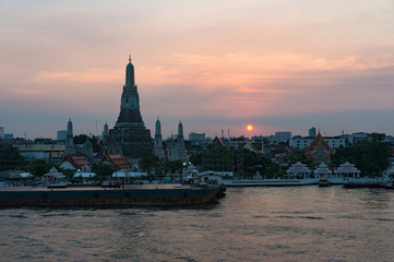 Fototapeta na wymiar Aerial view of Wat Arun, Temple of Dawn and wharf with sunset sky on the background. Urban Bangkok scene with Buddhist temple