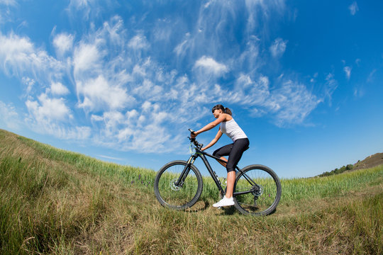 Sport bike woman on the meadow with a beautiful landscape