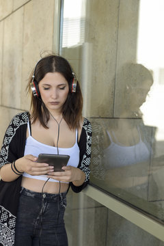 Young beautiful girl browsing a tablet and listening to the music with headphones