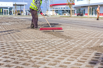 Worker is cleaning new parking place with red broom