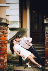 Young couple in near stairs outdoor. Having fun and embracing. Couple dance. Smile and kiss.