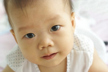 Face of cute Asian infant looking to someone.