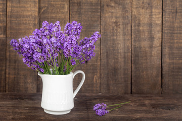 Bouquet of lavender in a white porcelain jug on wooden background