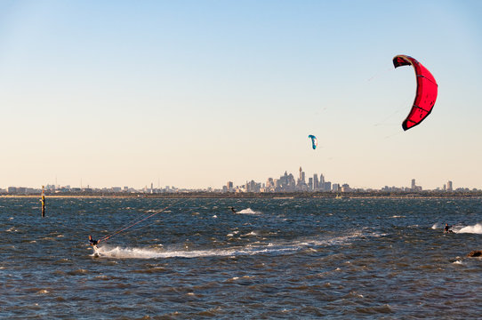 Ocean beach with kite surfers and windsurfers in a distance with Sydney cityscape on the background. Kurnell, Australia 