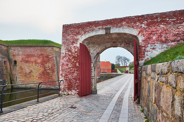 Red brick wall arched tunnel going over the cobblestone covered pathway that goes all the way around the Elsinore Castle in Denmark,