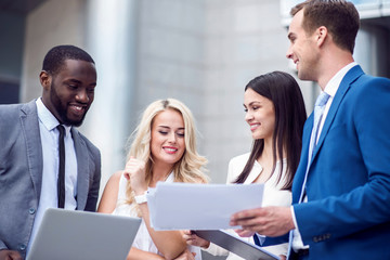 Positive colleagues standing near office building
