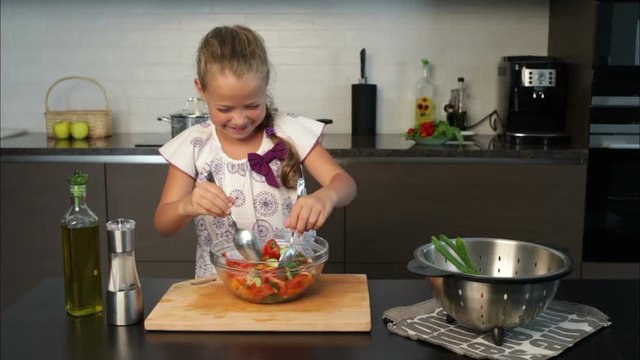 Little girl having fun during  preparing salad in the kitchen