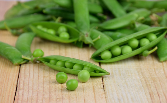 Pods of green peas close-up on wooden background.