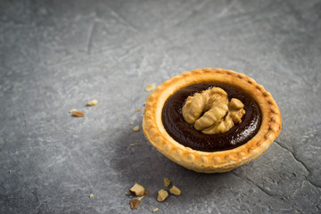 Small Chocolate Tart with Walnut on a gray stone background, spa