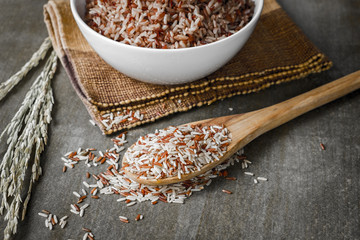 Brown Rice/Coarse rice on wooden spoon with boiled rice on background. Selective focus.