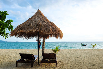 Wooden sun loungers stand on the Andaman Sea coast under dramati