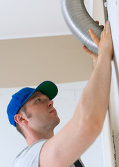 Man setting up ventilation system indoors.