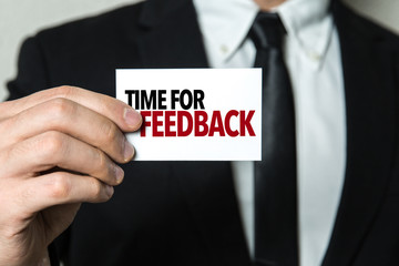 Business man holding a card with the text: Time for Feedback