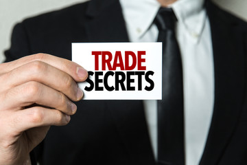 Business man holding a card with the text: Trade Secrets