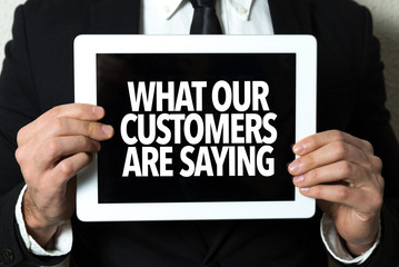Business man holding a tablet with the text: What Our Customers Are Saying