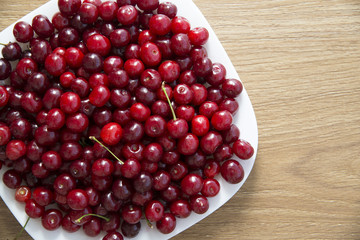 White dish up to the top filled with red ripe cherry 