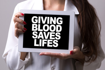 Female doctor holding a tablet with the text: Giving Blood Saves Life