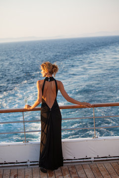 femme en robe de soir&eacute;e avec une coupe de champagne sur le pont d'un bateau