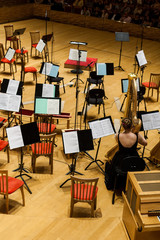 The orchestra pit in a concert hall. Chairs, musical instruments and wooden walls.