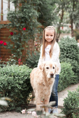 Child girl 3-4 year old standing with labrador retriever in park. Looking at camera. Togetherness.