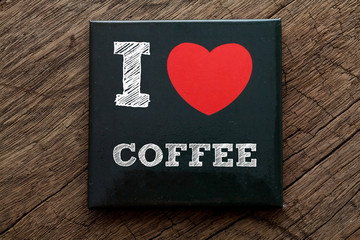 I Love Coffee written on black note with wood background