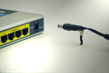 single mini worker try to carry power line to plug-in the router