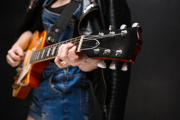 Fototapeta na wymiar Close up of girl's hands on guitar over black background.