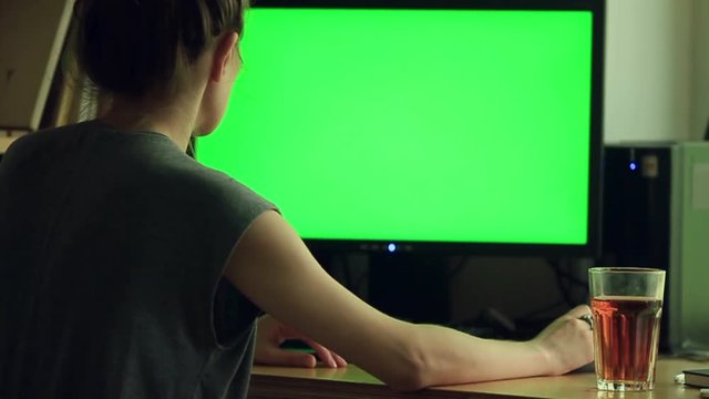 Over the shoulder shot of woman typing on a computer green screen