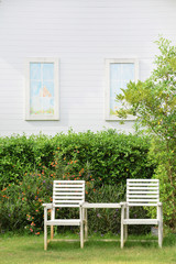 Garden with rustic white chair  with a white house wall background.