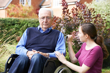 Fototapeta na wymiar Adult Daughter Comforting Senior Father In Wheelchair