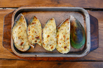 Mussels baked with cheese on the wood table