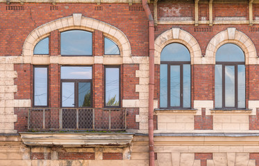 Three windows in a row and balcony on facade of urban apartment building front view, St. Petersburg, Russia.