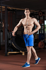 Fototapeta premium Man standing strong in the gym and flexing muscles