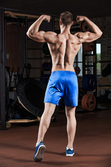Fototapeta premium Man standing strong in the gym and flexing muscles