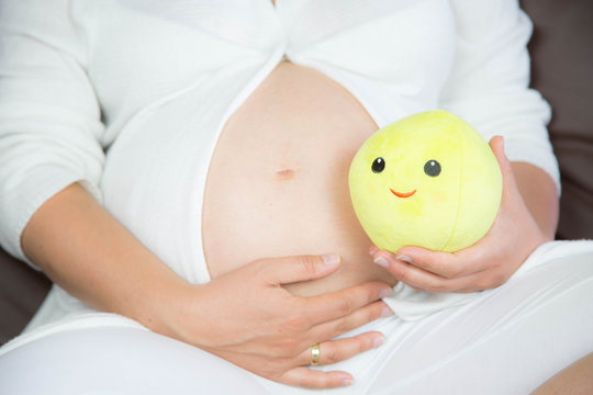 hochschwangerer Babybauch mit lachender Kugel, Blume, Schleife, Ente