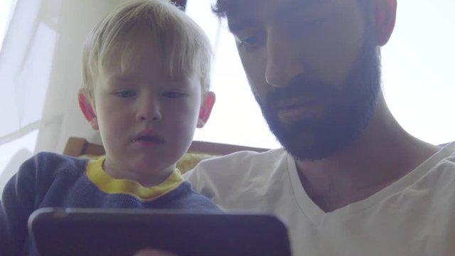 Close up shot of nephew and uncle playing games on a cell phone 