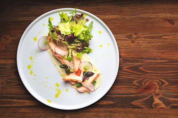 Mixed salad with warm salmon, crispy salted cucumber and cream cheese cream and herbs