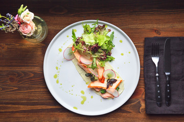 Mixed salad with warm salmon, crispy salted cucumber and cream cheese cream and herbs