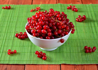 Fresh currants in a white bowl on a napkin on the green, bright