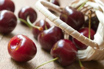 Cerises et petit panier en osier sur table en vieux bois