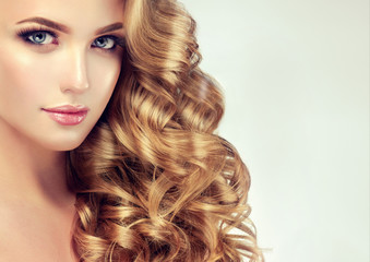 Beautiful girl with long wavy hair . Blonde model with curly hairstyle . 
