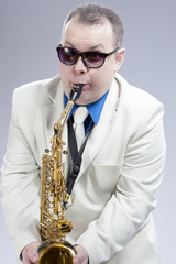Fototapeta premium Portrait of Funny Caucasian Saxophone Player in Sunglasses Performing Indoors